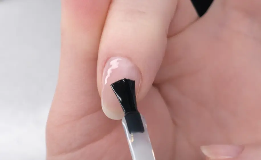Professional nail plate preparation showing base coat application technique for better product adhesion