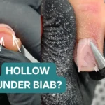 Before and after showing hollow gap under BIAB dual form overlay — left image shows air pocket beneath pink gel with arrows indicating void, right image shows carbide drill bit filing through hollow area for repair, demonstrated by Radina Ignatova, Artistic Touch Nail Training Academy