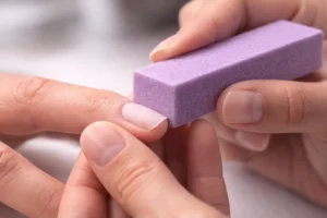 Professional demonstration of correct buffing technique on natural nail showing proper hand position and buffer angle